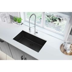 a black kitchen sink sitting on top of a counter next to a potted plant