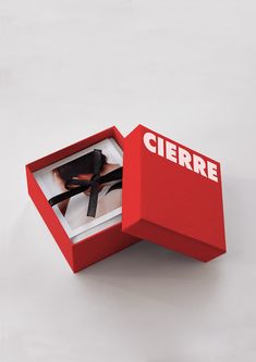 an open red box with scissors in it on a white surface, that says ciere