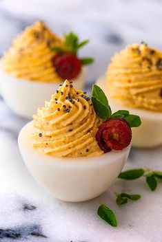 deviled eggs topped with mustard and chives on a marble table top, garnished with sprinkles