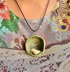 a woman wearing a necklace that has a bird in the bowl hanging from it's side