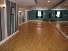 an empty room with hard wood flooring and blue walls, mirrors on the wall