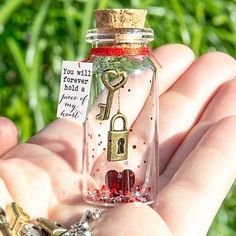 a hand holding a tiny glass bottle with a key in it and a note attached to the top