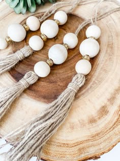 white beads with tassels and gold accents are arranged on a piece of wood