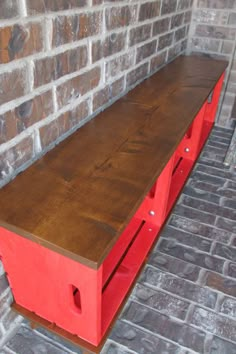 a red bench sitting in front of a brick wall