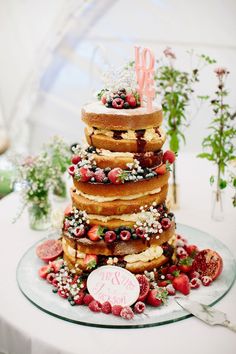 a wedding cake made out of donuts and strawberries is displayed on a table