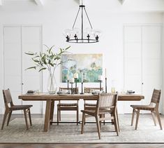 a dining room table and chairs in front of a painting on the wall with white walls