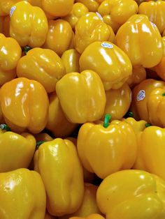 many yellow peppers are stacked up together