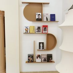 shelves with books and magazines on them against a white wall