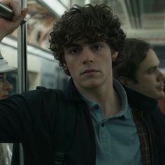 the young man is holding his cell phone up to his ear while riding on the subway