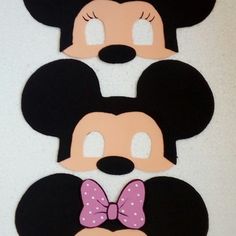 three mickey and minnie mouse cut outs on a white surface with pink bows around their ears