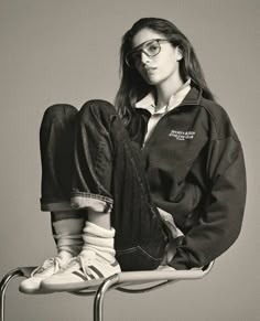 a woman sitting on top of a chair with her legs crossed in front of her face