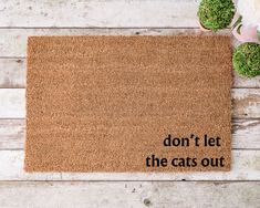 a door mat with the words don't let the cats out on it next to flowers