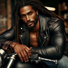 a man with dreadlocks sitting on a motorcycle wearing a leather jacket and jeans