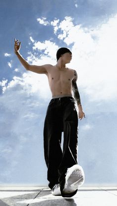 a man with no shirt on riding a skateboard in the air and holding his hand up