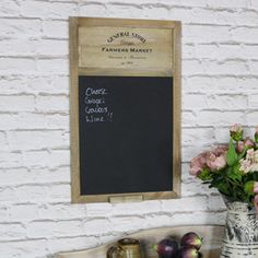 flowers and fruit are sitting on a table next to a chalkboard