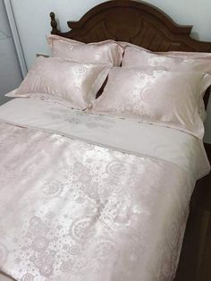 a bed with pink sheets and pillows on top of it