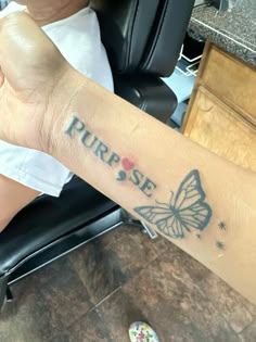 a person with a butterfly tattoo on their arm that says,'purpose'and is sitting in a chair