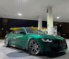 a green sports car parked in front of a gas station