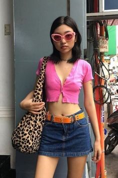 a woman in pink shirt and leopard print handbag standing next to a blue wall