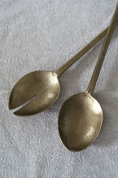 two metal spoons sitting on top of a white cloth