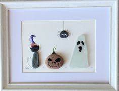 three halloween decorations are hanging in a white frame