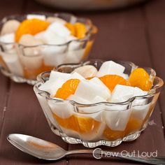 small glass bowls filled with oranges and marshmallows on top of a wooden table