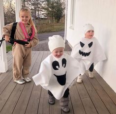 two children dressed up in halloween costumes standing on a porch with one holding a leash