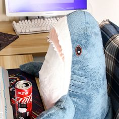 a stuffed shark sitting in front of a computer