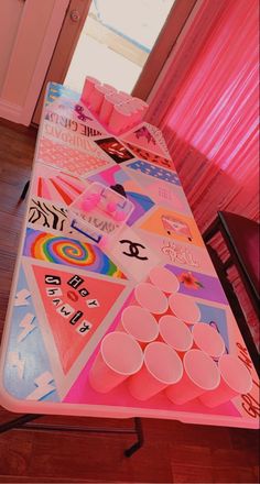 a long table with cups on it in front of a pink curtained room door