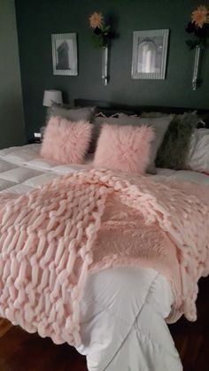 a bed with pink fluffy pillows on top of it