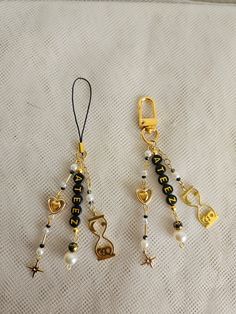 two gold and black beaded keychains on a white cloth with star charms hanging from them