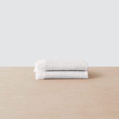 two white towels sitting on top of a wooden table