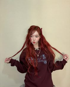 a woman with long red hair standing in front of a wall