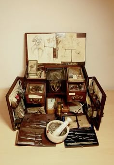 an open suitcase with many items in it sitting on a wooden table next to a wall