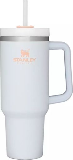 the stanley travel mug is white and has an orange logo on the side, along with a straw sticking out of it