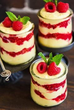 three small desserts with raspberries on top