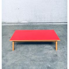 a red coffee table sitting on top of a cement floor next to a white wall