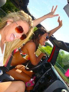 two beautiful young women riding in the back of a car