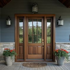 two potted flowers sit on the front porch of a house with double doors and sidelights