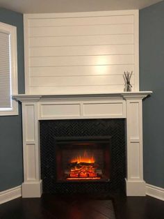 a fireplace in a room with blue walls and white trim on the wall, along with wood flooring