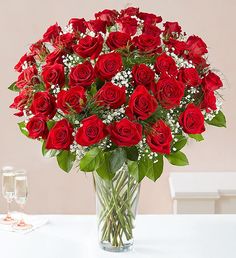 a vase filled with red roses and baby's breath on top of a table