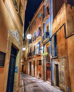 an alley way with several buildings and lights on the building are lit up at night