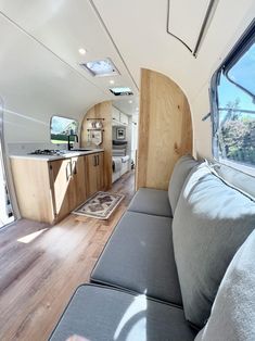 the interior of a camper with wood flooring and couch in front of it