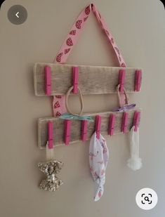 a wall hanging made out of wood with pink ribbon and key holders attached to it