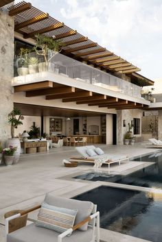 an outdoor swimming pool with lounge chairs and potted plants next to it on the patio