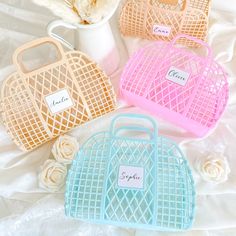 four purses sitting on top of a bed next to white flowers and a vase