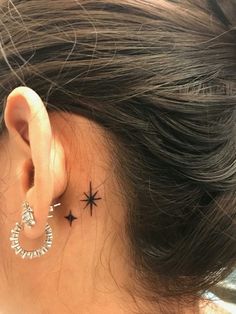 a woman's ear has a small star tattoo on it