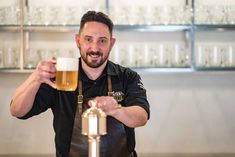 a man in an apron holding a beer mug