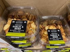 three plastic containers filled with garlic and herb crackers next to other packaged food items