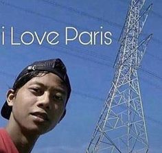 a young man standing in front of a tower with the words i love paris on it